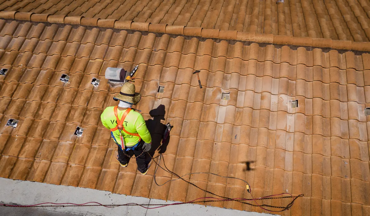 Instalador de VOLT Home con arnés de seguridad trabajando en un techo de tejas en Florida.